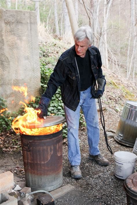 Steven Forbes-deSoule during a raku firing, flames rising from the reduction can