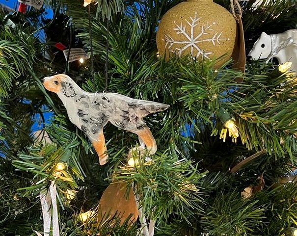 A hand-painted ceramic dog ornament on a Christmas tree