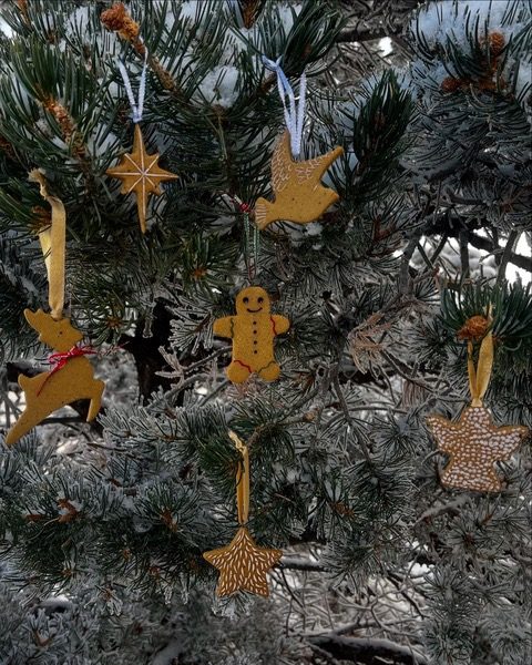 Clay gingerbread, star, dove and reindeer ornaments in a snowy pine