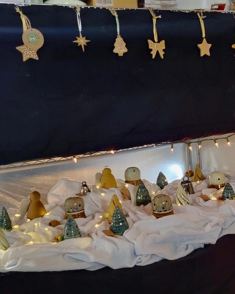 A studio shelf of ceramic holiday pieces on white cloth